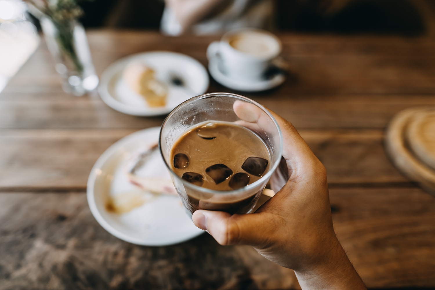 Personal perspective of a man holding a glass of iced coffee