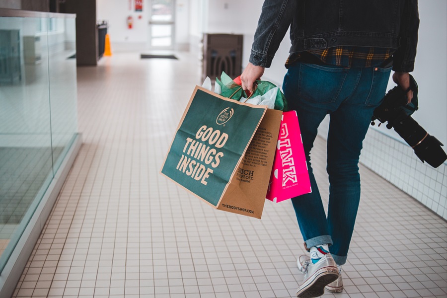 A man carrying shopping bags in a mall.